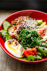delicious and appetizing salad egg, tomato, spinach, cucumber, cheese, cilantro, lies on a red plate in a restaurant