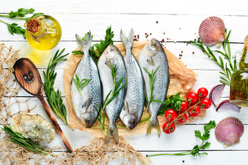 Raw fish with lemon, salt and rosemary. On a white wooden background. Top view. Free copy space.