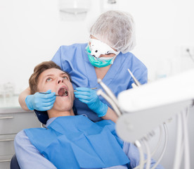 Dentist female in uniform is examinating of male in dental clinic