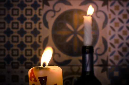 two burning candles on tile background, front view take two