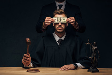 cropped view of man standing and covering face of judge with bribe on black