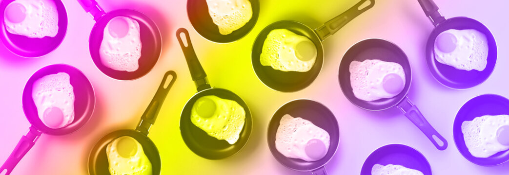 Creative food pattern with fried eggs on pans in trendy neon colors. Rainbow gradient background. Top view.