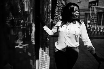 Fototapeta premium Formally dressed african american business woman in white blouse and red trousers with walking stick at hand. Successful dark skinned businesswoman.