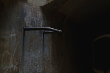 A bar handle of the exit ladder down inside the dark street tunnel. 