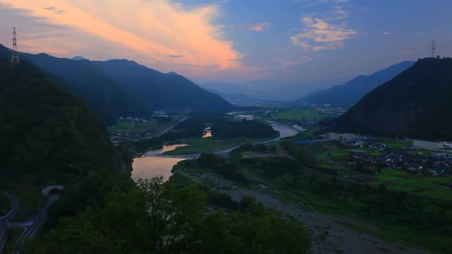 Tilt up of Chikuma River in mountain landscape at sunrise, Japan