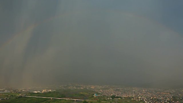 Zoom out of rainbow over Chikuma River, Ueda City and Uedahara, Japan