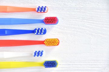 Colorful toothbrushes with selective focus on blurred neutral background. Dental tools for daily teeth protection. Multicolored plastic toothbrush with bright bristles with soft focus. Oral hygiene 