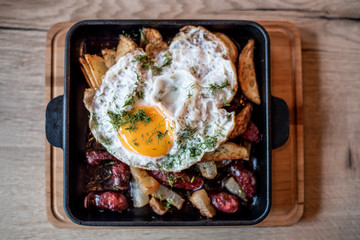 The pan has a baked tasty dish - potatoes with bacon and smoked sausages and fried egg. Not very useful but a delicious dish