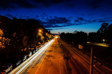 Obraz premium Nightscape road and rail track with car moving light trail long exposure photography in a city landscape during the night time