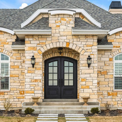 Square Home facade with stone brick wall double glass paned door and arched windows