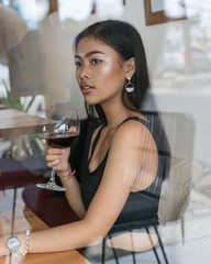 Asian girl  in a cafe. Beautiful Balinese women with glass of wine