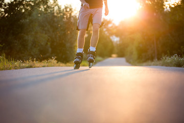 Young man enjoying roller skating on the bicycle path during lovely summer sunset