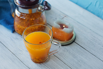 sea buckthorn tea on a white wooden background with candles