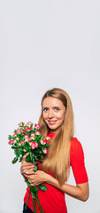 Female holiday. Vertical banner photo of cute lovely blonde woman with large bouquet of roses while she looks on camera. Holidays and gifts concept. Women's day