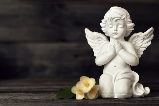 Little guardian angel and jasmine flowers on wooden background