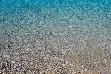 Clear sea water texture, top view of the rocky bottom. Transparent tropical ocean, coral reefs, abstract emerald water surface background