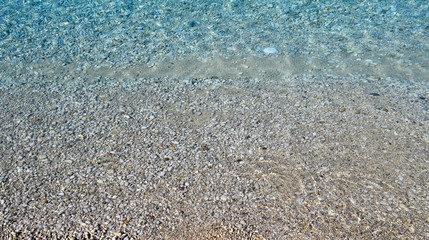 Clear sea water texture, top view of the rocky bottom. Transparent tropical ocean, coral reefs, abstract emerald water surface background
