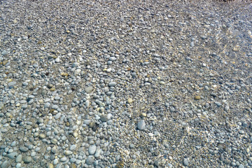 Sea wave moves to a pebble beach. Summer sunny day. View from above