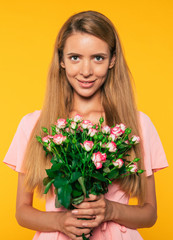 Close up portrait of tender attractive blonde woman with big bouquet of roses isolated on yellow wall background. Holidays and gifts concept. Women's day. St. Valentine's day