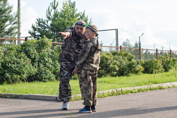 Fototapeta premium Man and boy playing in lasertag shooting game, father and son with a gun, war simulation.
