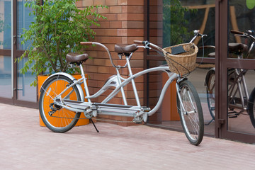 Fototapeta na wymiar gray tandem bicycle in front of a street cafe on a summer day