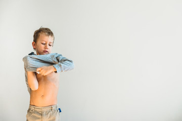 Child trying to take off his shirt and undress on his own.