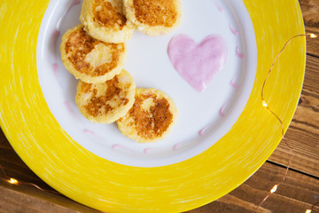 tasty cheese pancakes on a yellow plate stand on a wooden board-day in love, breakfast in bed