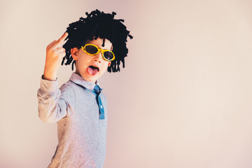 Child with a Jamaican wig showing middle finger to insult.