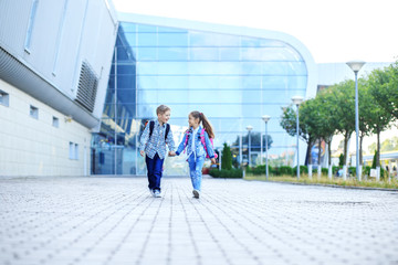 Obraz premium Children hold hands and go. Boy and girl communicate. The concept of childhood, family, education.