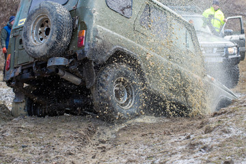 Fototapeta na wymiar Rally on Russian SUVs in the mud in winter, Trapped all-terrain vehicle pulled out of the river 