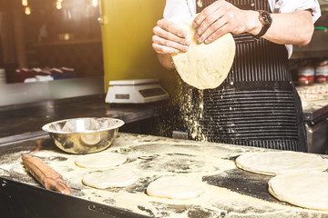 Professional chef cooking in the kitchen restaurant at the hotel, preparing dinner. A cook in an apron makes a salad of vegetables and pizza.