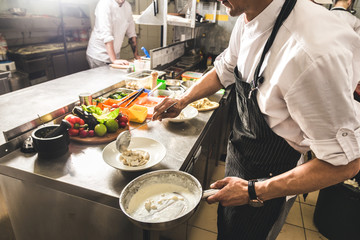 Professional chef cooking in the kitchen restaurant at the hotel, preparing dinner. A cook in an...