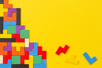 Different colorful shapes wooden blocks on yellow background. Top view