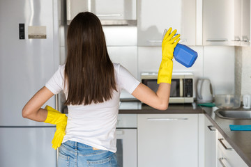 A young woman from a professional cleaning company cleans up at home. A man washes the kitchen in yellow gloves with cleaning supplies stuff.