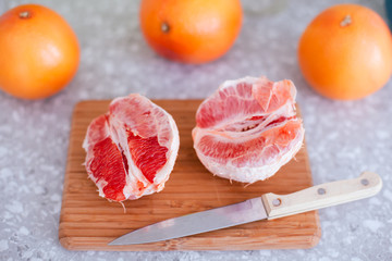 Ripe grapefruits and knife on cutting board.
