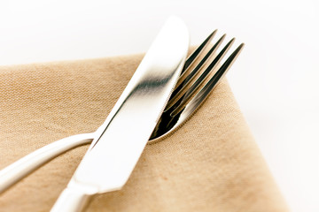 Table knife and fork on beige napkin.