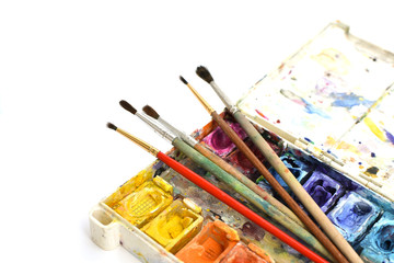 Obraz premium Art brushes and watercolor paints on isolated white background. Accessories and tools for creativity. Painting and drawing hobby. Back to school. Place for text. Copy space