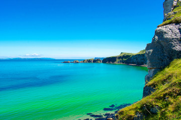 Fototapeta premium Carrick a Rede Rope Bridge in Ballintoy, Northern Ireland. Beautiful Landscape on Coast of Atlantic Ocean, Clear blue and green water 