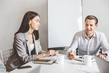Fototapeta premium A team of young office workers, businessmen with laptop working at the table, communicating together in an office. Corporate businessteam and manager in a meeting. coworking.