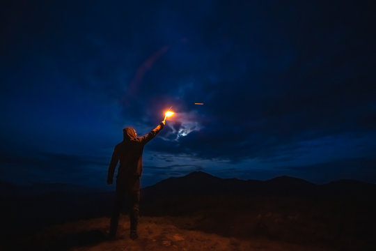 The male with a firework stick standing on a mountain. evening night time
