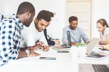 A team of young office workers, businessmen with laptop working at the table, communicating together in an office. Corporate businessteam and manager in a meeting. coworking.