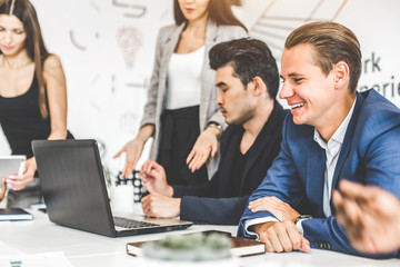 A team of young office workers, businessmen with laptop working at the table, communicating together in an office. Corporate businessteam and manager in a meeting. coworking.