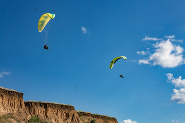 paraglider flying in the blue sky among the white clouds. Paragliding