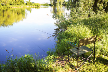 Armchair for fishing on the lake. Fishing rod in the water