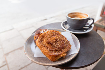 Warm cinnamon bun with icing sugar with cup of coffee