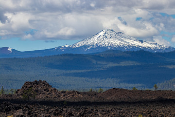 Fototapeta na wymiar Snow capped mountain with lava rock in the foreground