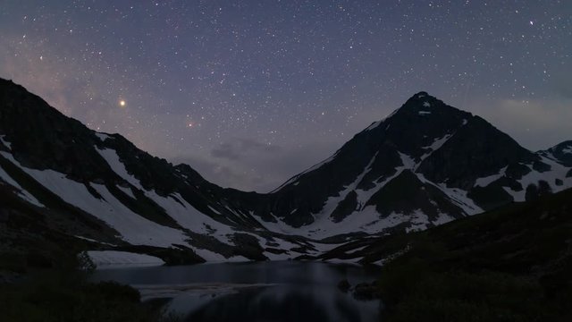 Night sky of stars and Milky way time lapse over the mountain. Milky way Galaxy and stars above mountain. Caucasus Mountain and Arkhyz lake time lapse.