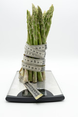 Asparagus surrounded by a medical tape on weighing scale for diets