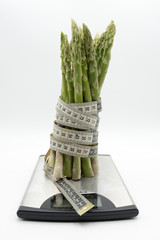Asparagus surrounded by a medical tape on weighing scale for diets