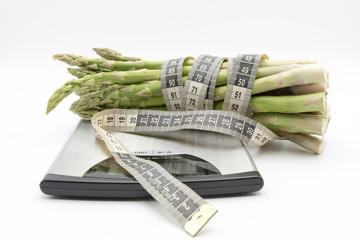 Asparagus surrounded by a medical tape on weighing scale for diets